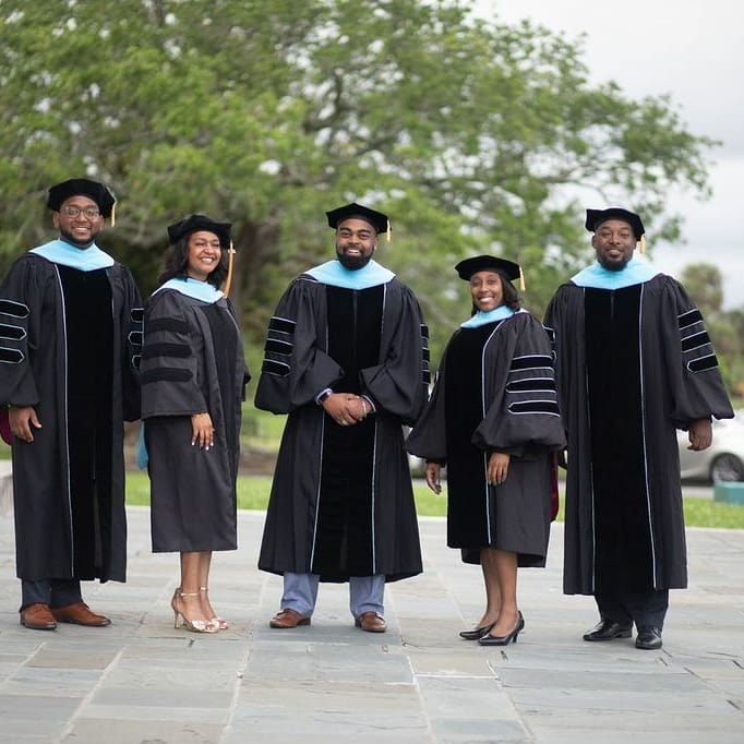 Five graduates of the Doctorate In Executive Leadership Program smiling in UHC regalia