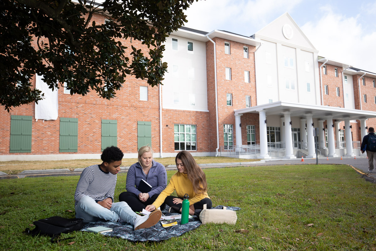 Picture of students working on the grass outside the UHC Residence Hall